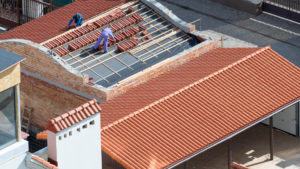 Roofing contractors working on tile roof replacement from above